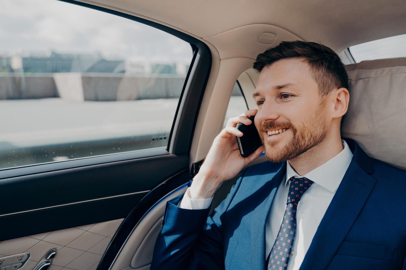 happy-business-owner-sitting-on-back-seat-in-car-and-talking-on-phone-free-photo